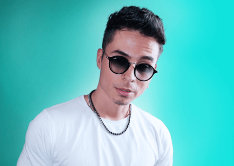 Reykon in a white t-shirt poses for a picture.